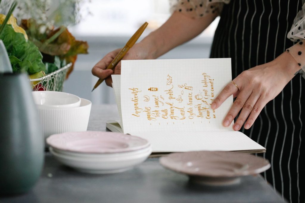 Une main note une astuce dans un carnet, dans une cuisine