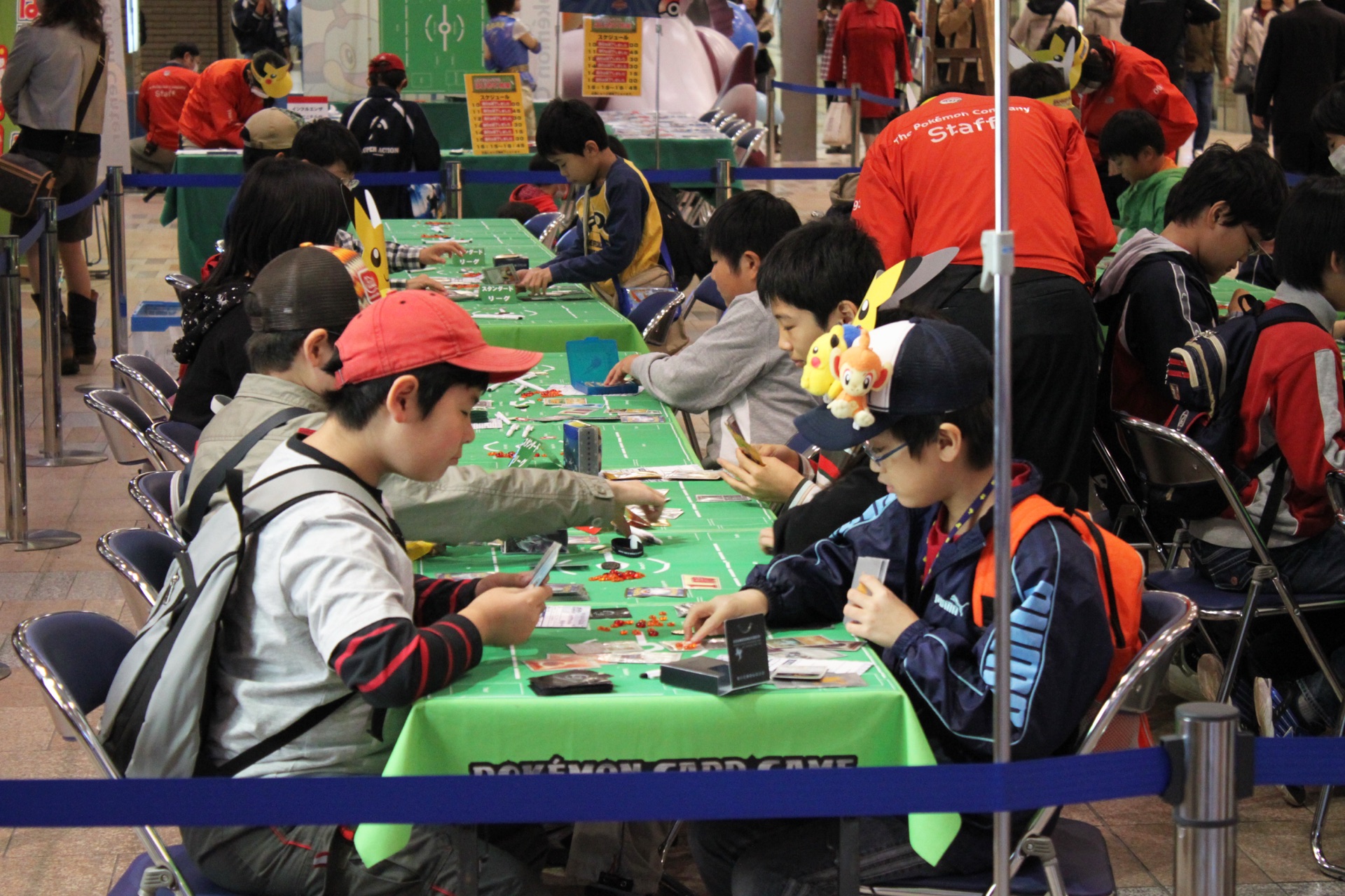 cartes Pokémon étalées et manipulées sur une table pendant une partie, gros plan sur les mains des joueurs