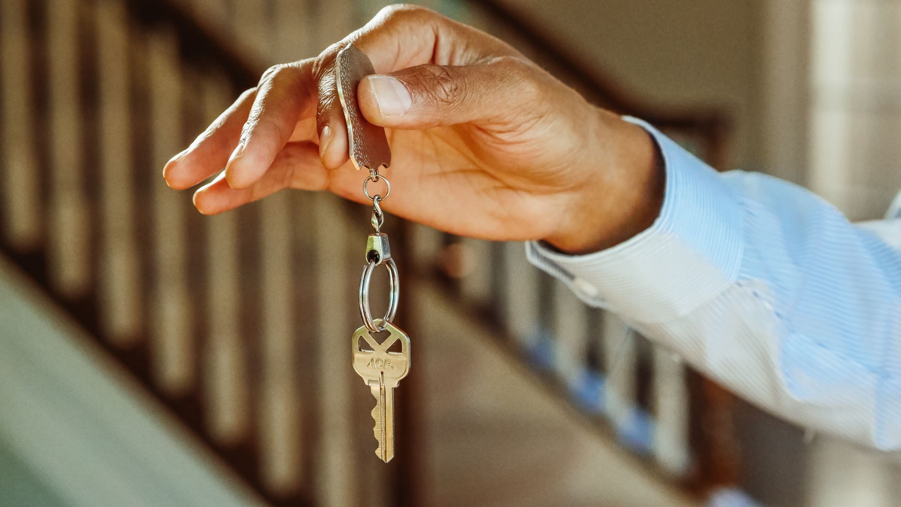 main tenant un trousseau de clés au-dessus d'une table, gros plan