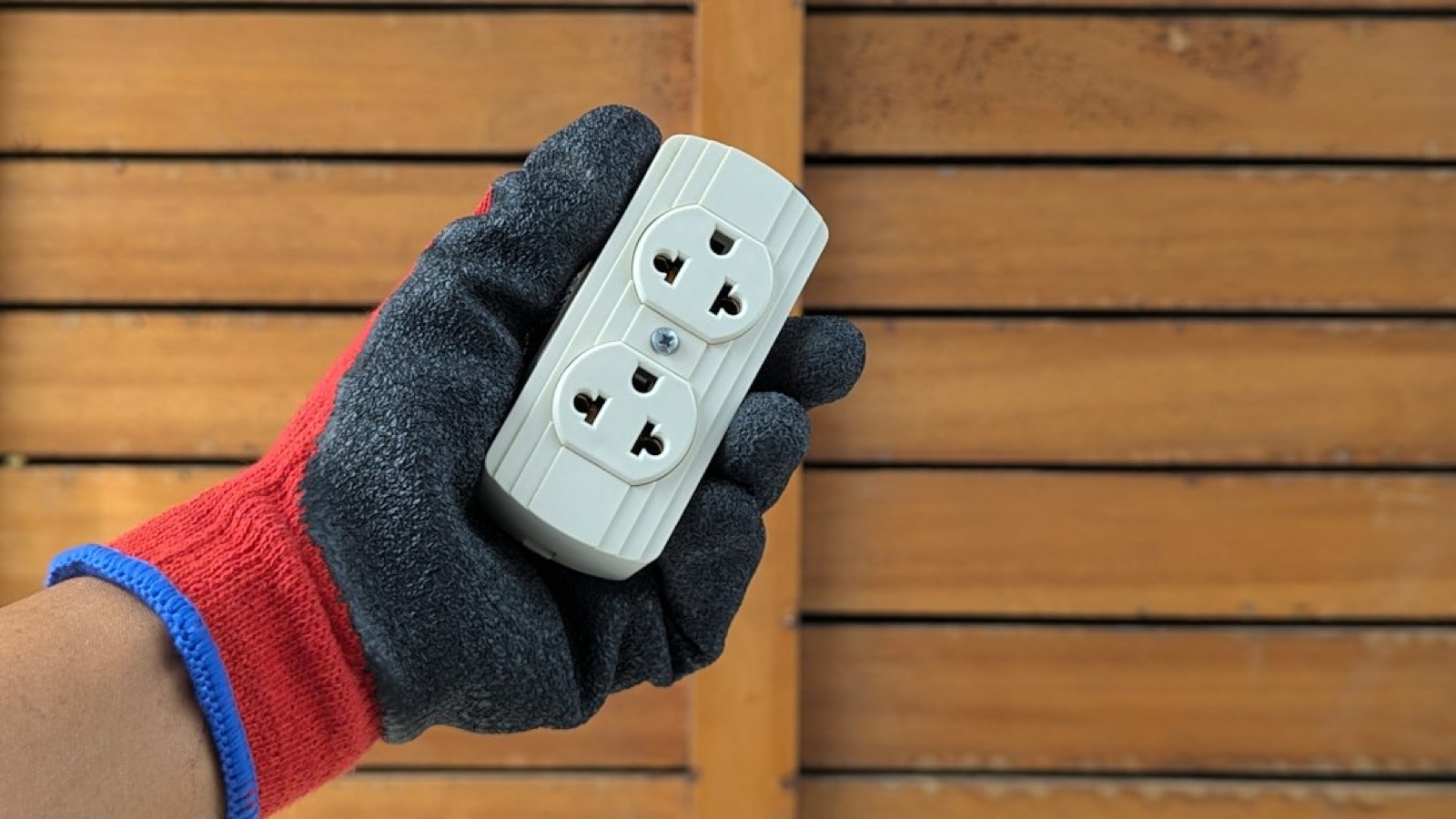 électricien testant une prise murale avec un multimètre