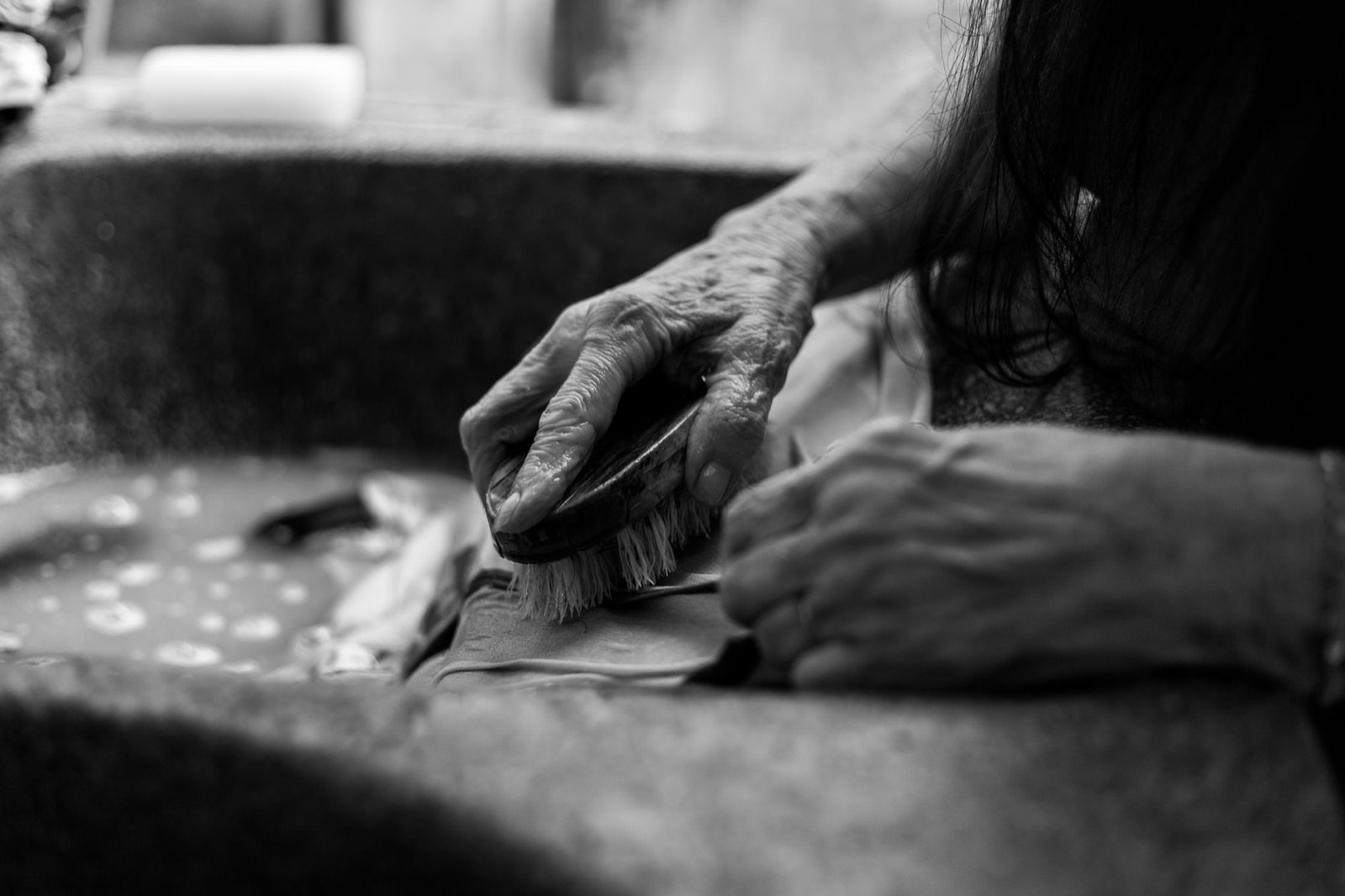 Lavage d'un chapeau à la main dans une bassine d'eau savonneuse